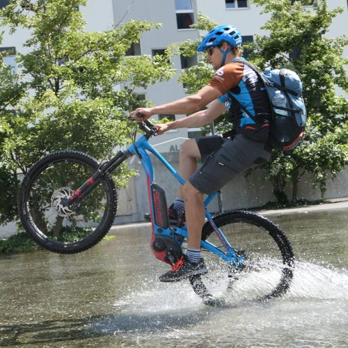 beitune Guide André fährt mit dem E-MTB Wheelie.