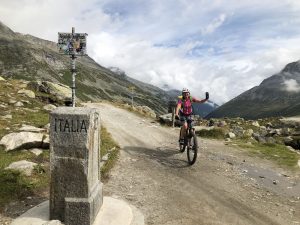 Mountainbikerin am Grenzstein am Pfitscherjoch auf dem Weg von Tirol nach Südtirol bei der beitune Frauen-Transalp